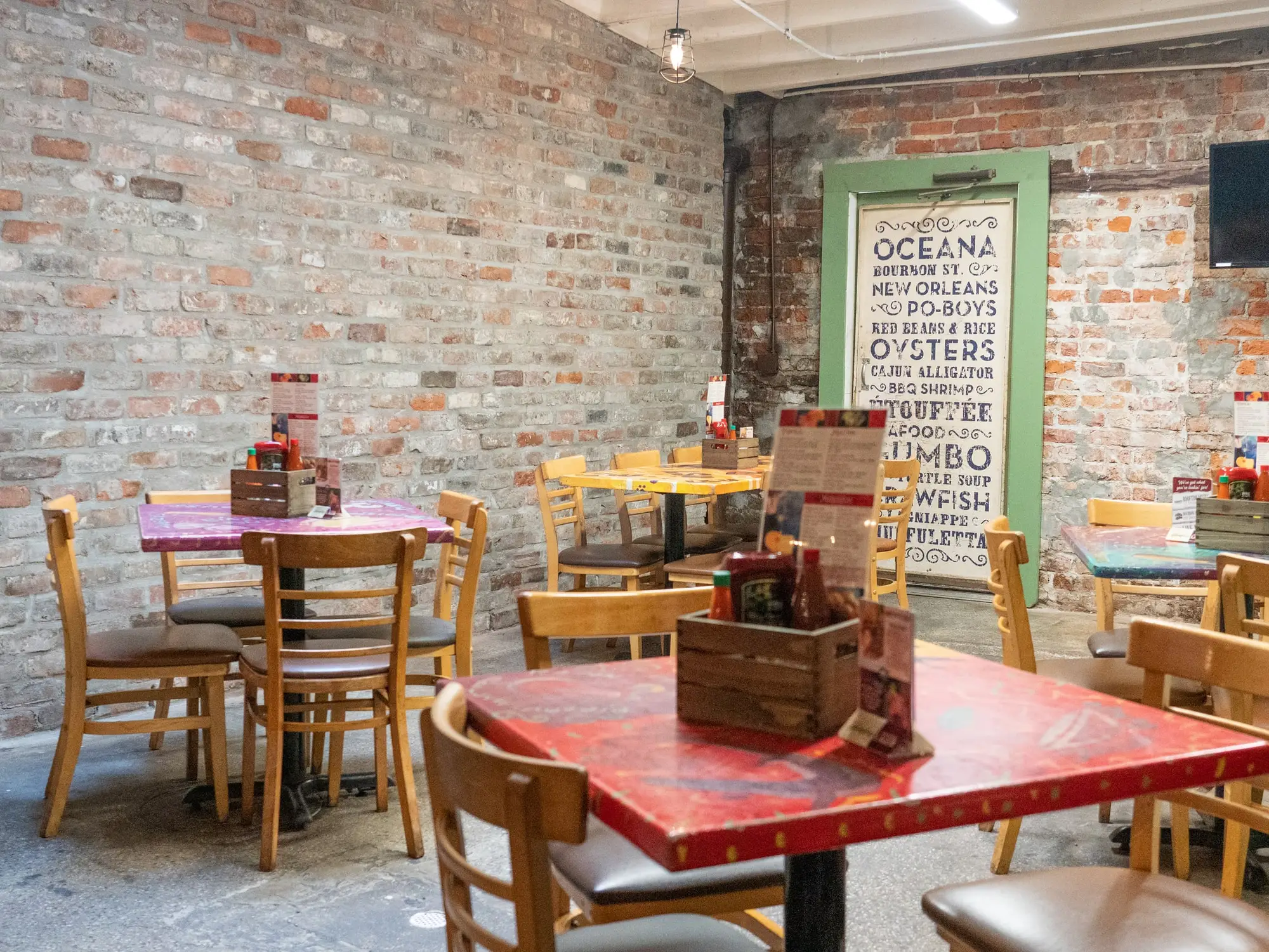 Colorful painted tables against exposed brick in Oceana Grill’s dining room